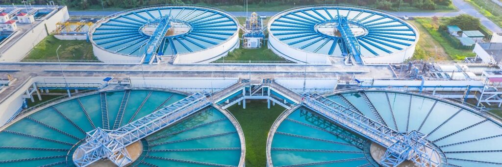 Aerial view of a modern water treatment plant with large circular clarifiers and filtration units, showcasing advanced purification technologies used by On Take Water for clean, safe, and sustainable drinking water.

