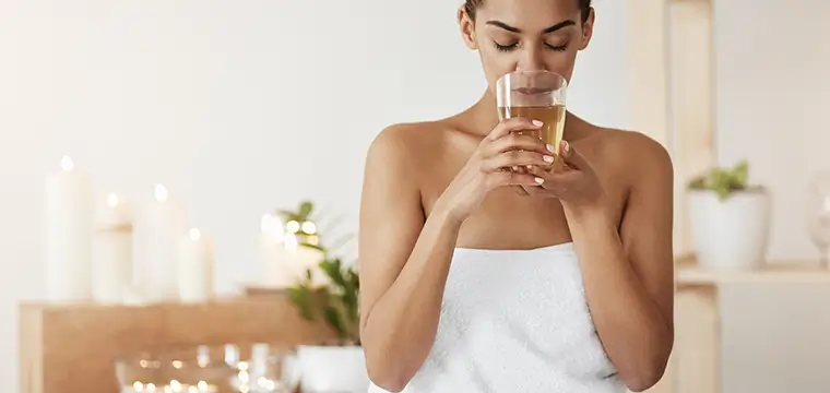 "Relaxed woman in a spa-like setting drinking infused water, promoting lymphatic drainage and detox — illustrating how staying hydrated with On Take Water supports the lymphatic system for natural cleansing and immune health."