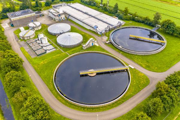 "Aerial view of a modern wastewater treatment plant with circular clarifiers, aeration tanks, and surrounding green landscape."