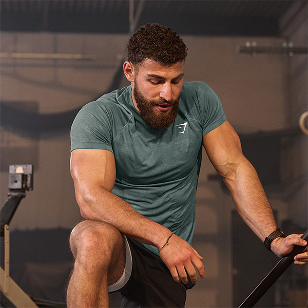 A muscular man resting after exercise in a gym, emphasizing the need to understand sweat rate for effective on take water.